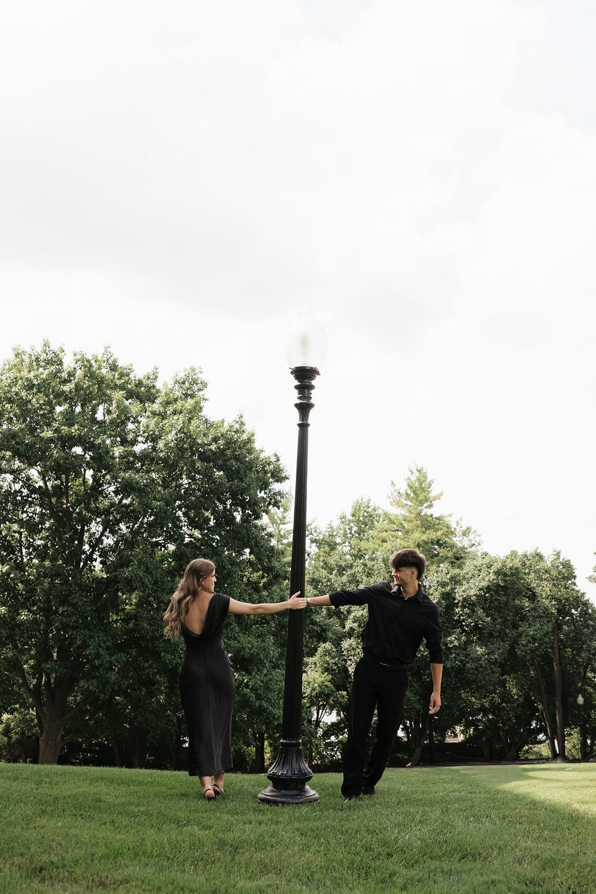Max and Angela holding a lamp post between them in a park