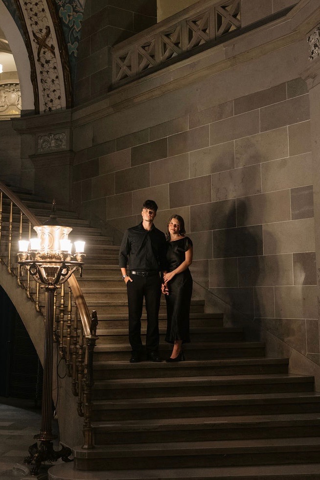 Max and Angela on a grand stone staircase by lamplight